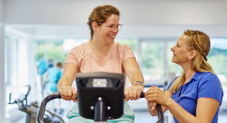 Frau auf Ergometer bei Geräteeinweisung