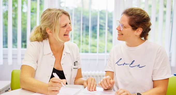 Diabetesberatung Eine Diabetesberaterin und eine Patientin sitzen am Tisch und besprechen die Diabetestherapie