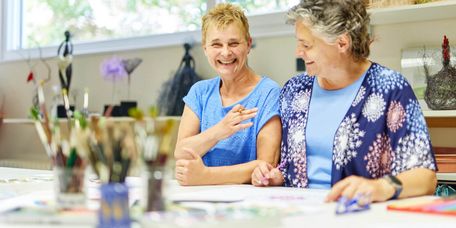 Zwei Frauen sitzen zusammen bei der Maltherapie