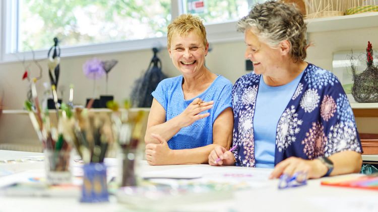 Zwei Frauen sitzen zusammen bei der Maltherapie