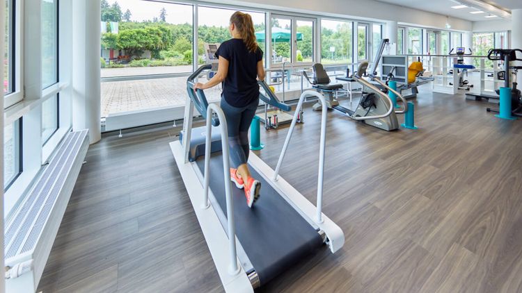 Im Sportpark trainiert eine Frau auf dem Laufband