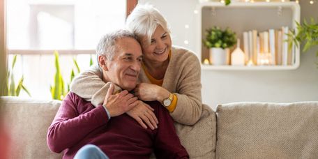 Ein älteres Pärchen umarmt sich auf dem Sofa