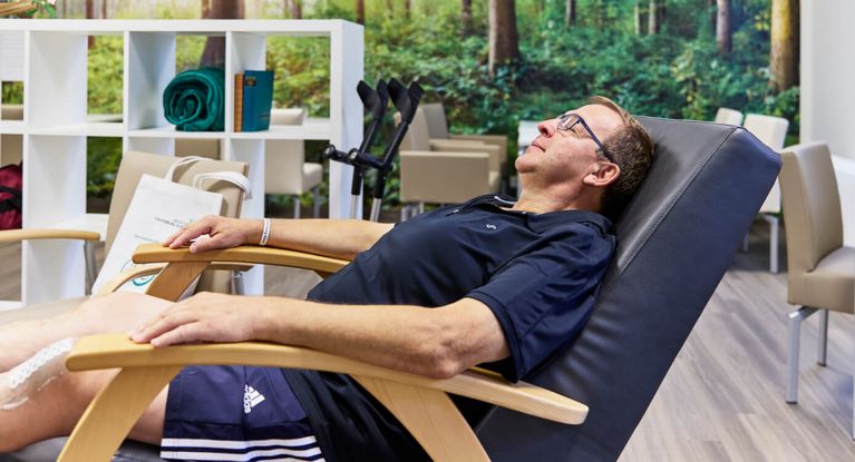 Ein Mann ruht sich im Ruheraum auf einer Liege aus