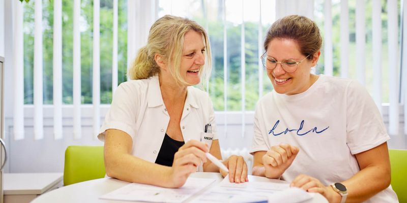 Eine Diabetesberaterin und eine Patientin sitzen am Tisch und besprechen die Diabetestherapie