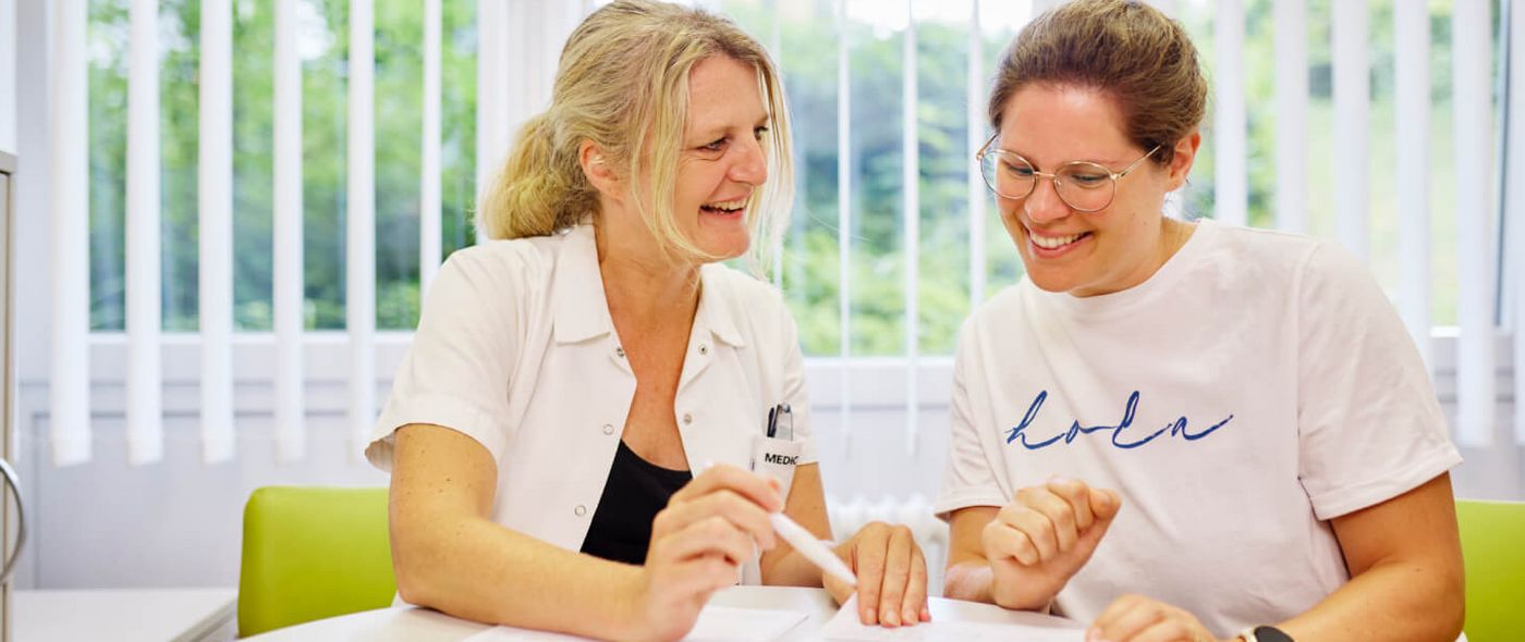 Eine Diabetesberaterin und eine Patientin sitzen am Tisch und besprechen die Diabetestherapie